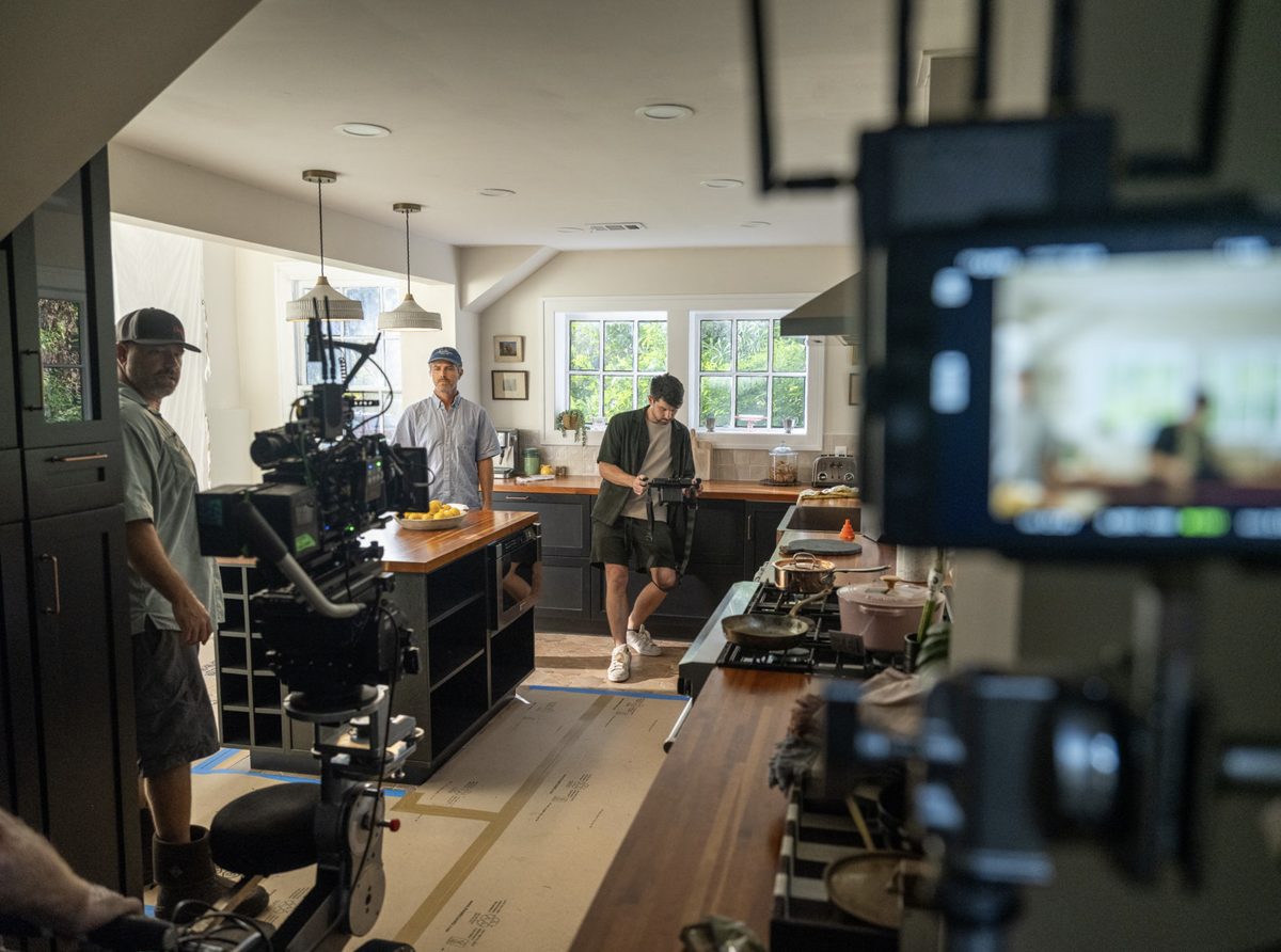 John Wikstrom directing on set in a kitchen, with camera crew